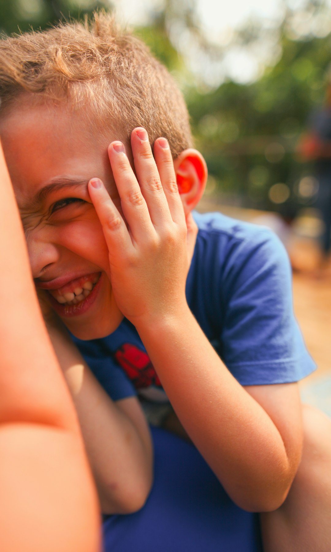 Boy laughing with his hand on his face