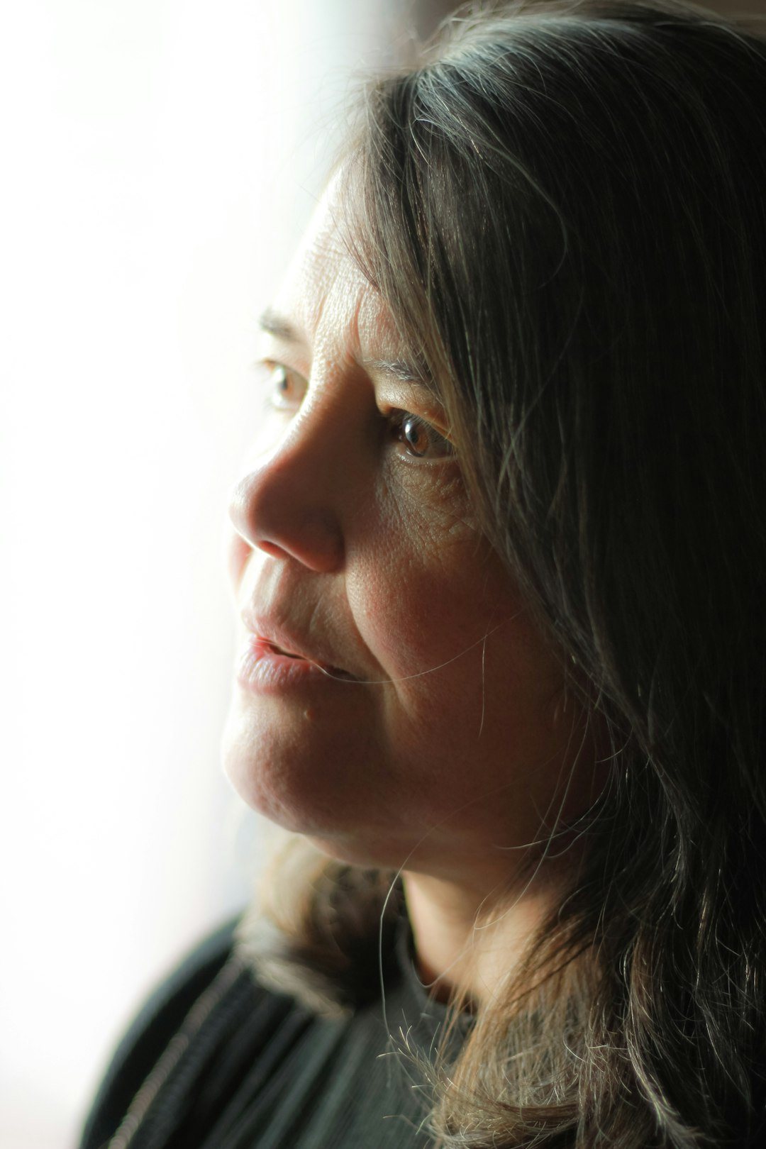 Woman looking out a window in soft light