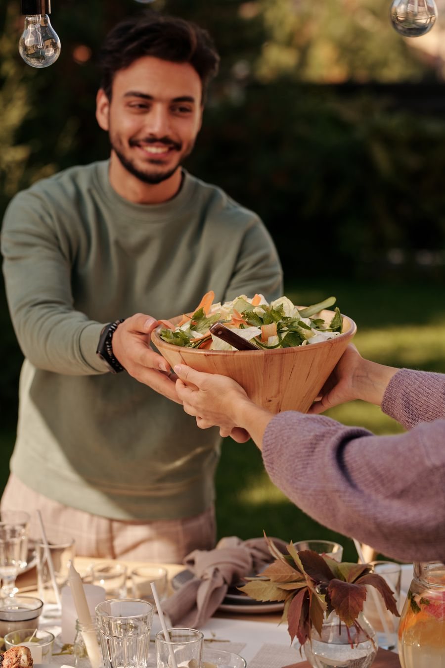 Man passing a salad bowl at a shared table