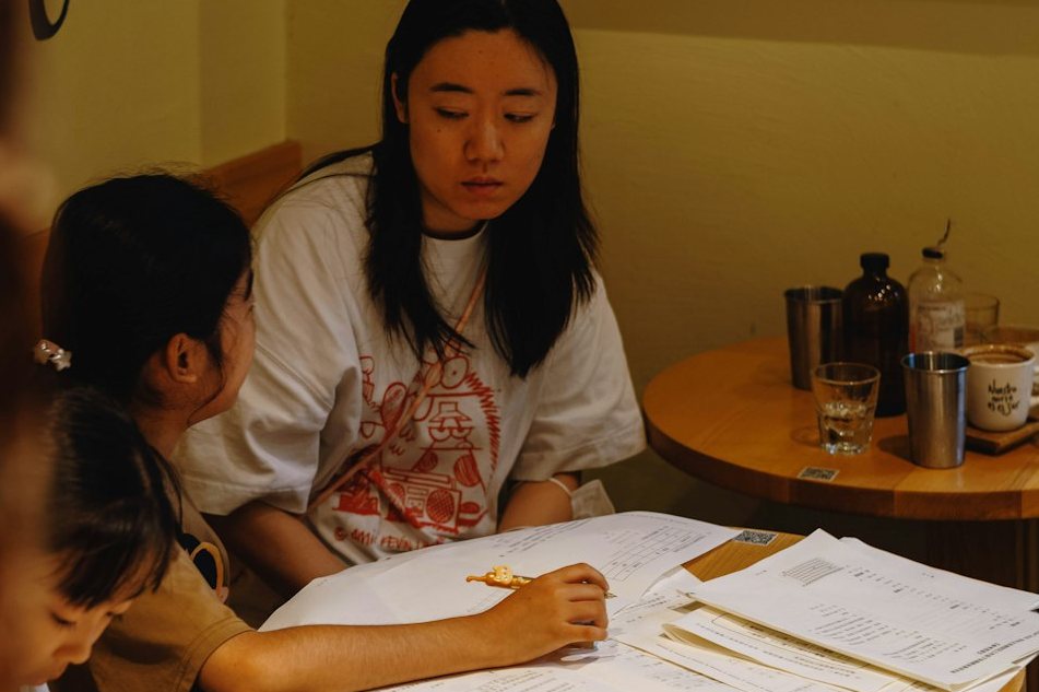 Woman helping a girl with schoolwork at a table