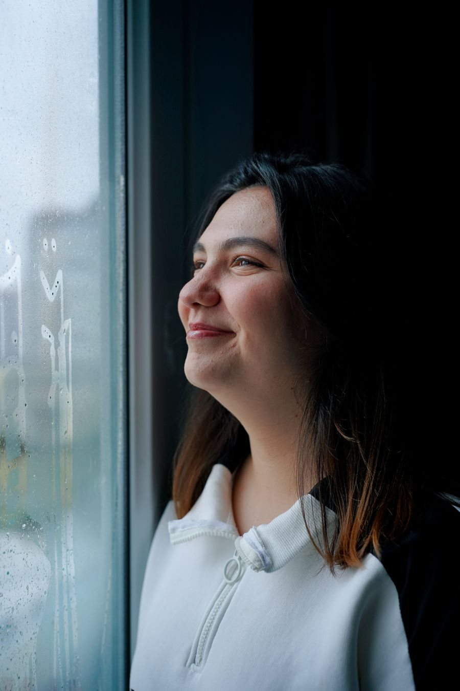 Woman smiling as she looks out a window