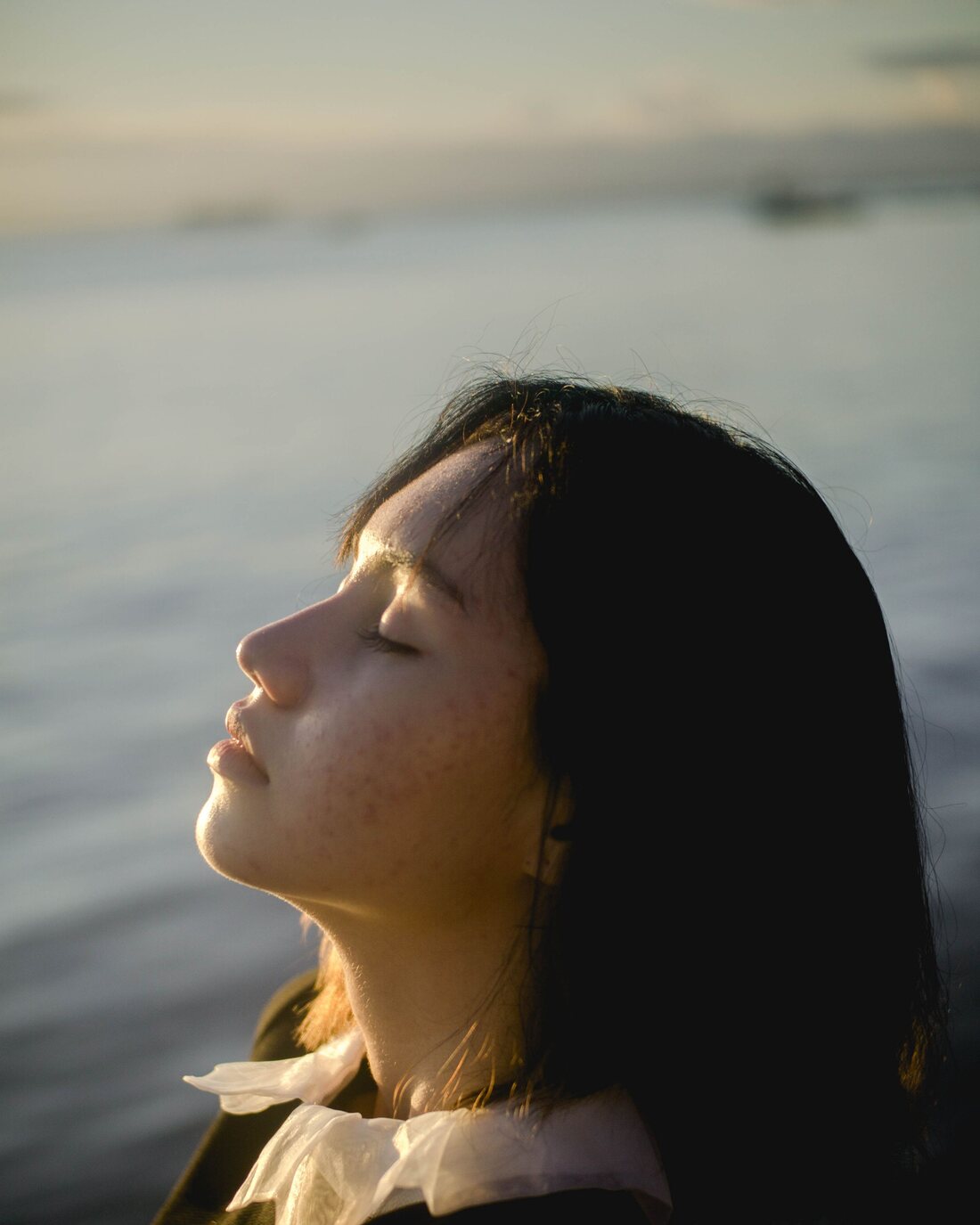 Woman with her eyes closed by the water